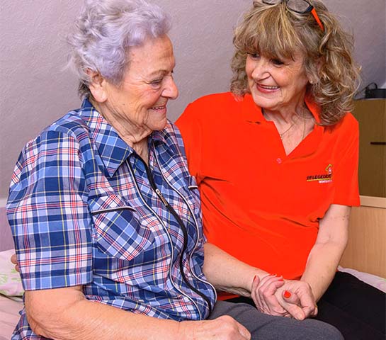 Seniorin wird von einer Pflegekraft betreut.